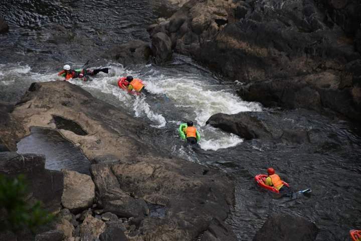 a group of people on a rock next to water