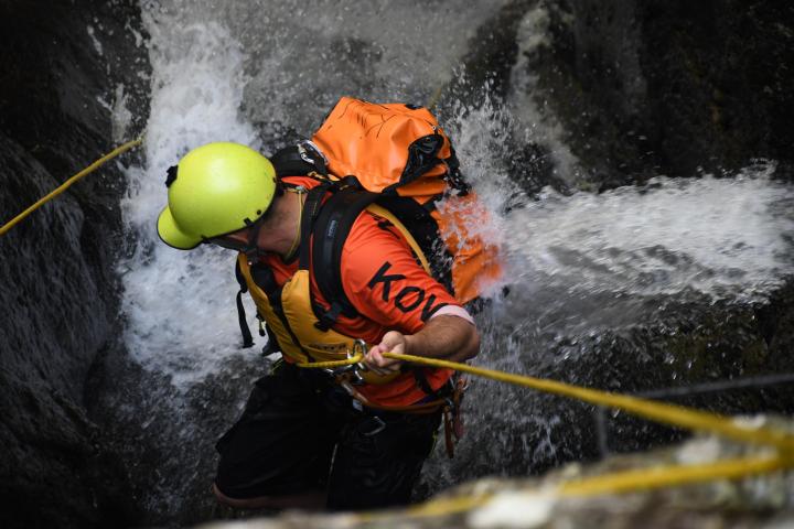 a man wearing a helmet riding a wave on a surfboard in the water